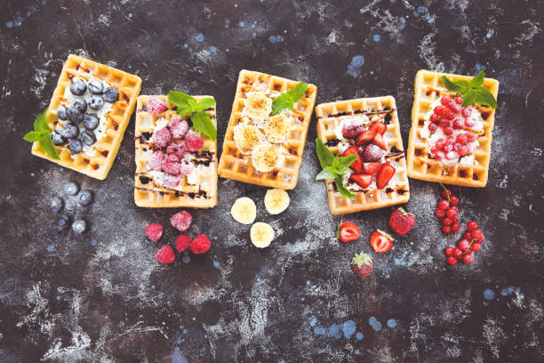 gofres sabrosos con bayas frescas y crema batida sobre fondo negro - gourmet waffle raspberry berry fruit fotografías e imágenes de stock