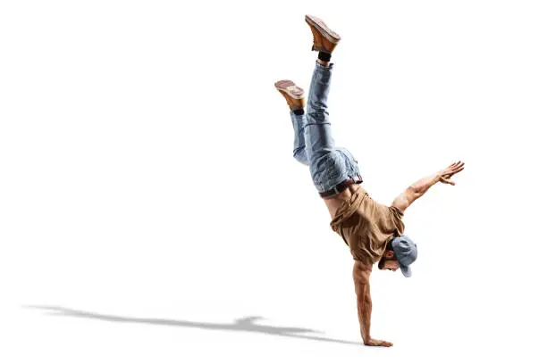 Young fit man in jeans performing a one hand stand isolated on white background