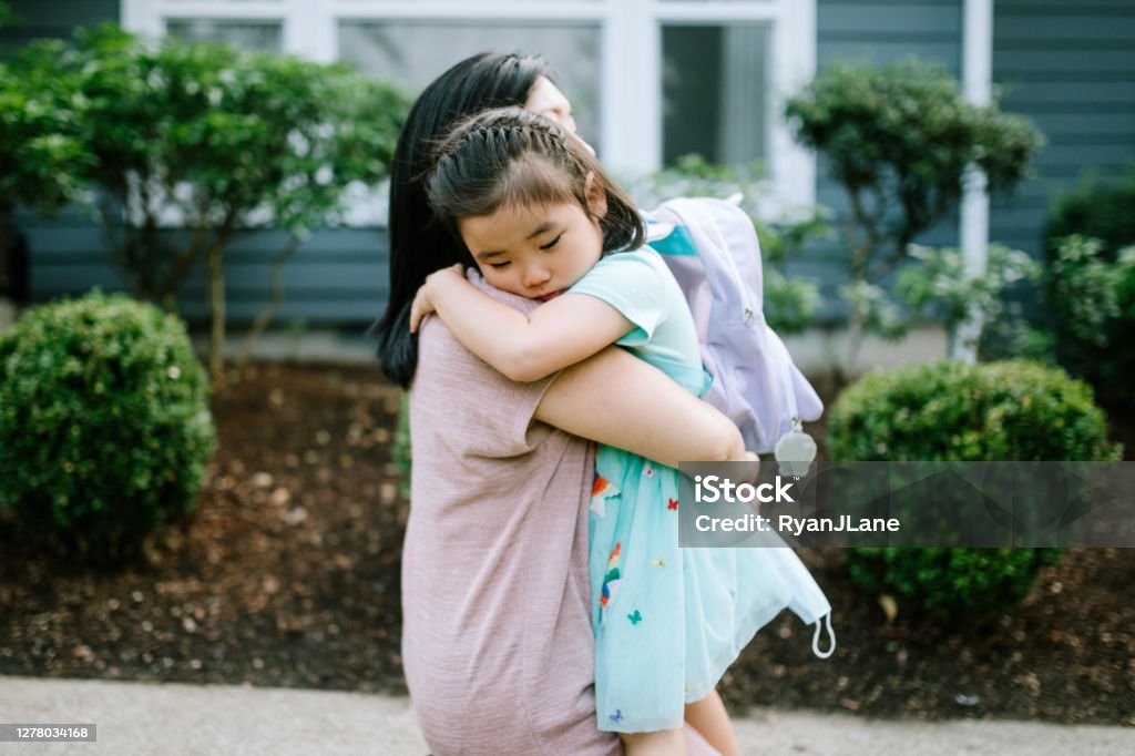 Girl Hugs Her Mother On First Day of School A Korean woman holds her daughter tightly in an embrace, the girl feeling anxious going back to school. Child Stock Photo