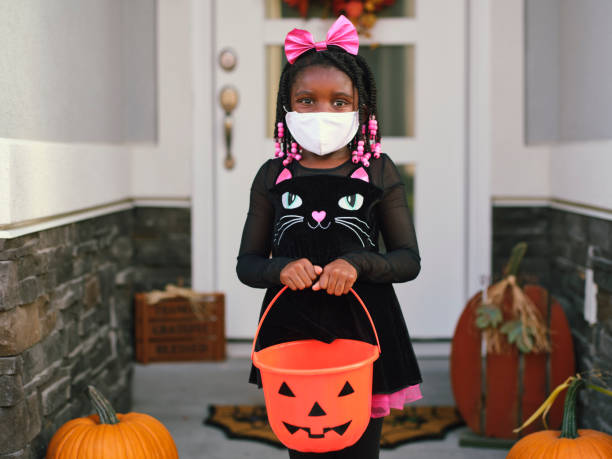 Halloween Children Trick or Treating Wearing Facemasks Children trick or treating on Halloween wearing facemarks for protection. black cat costume stock pictures, royalty-free photos & images