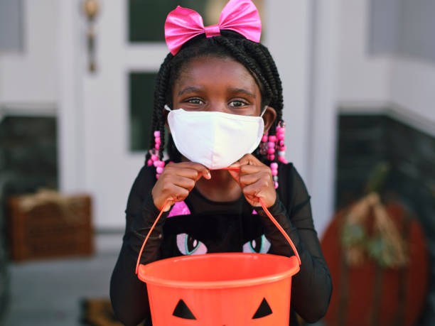 Halloween Children Trick or Treating Wearing Facemasks Children trick or treating on Halloween wearing facemarks for protection. black cat costume stock pictures, royalty-free photos & images