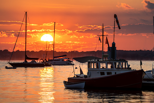 beautiful orange sunset in Newport RI with silhouetted boats in the water