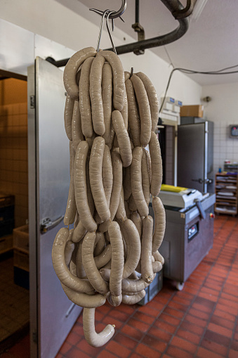 hanging fresh sausages, bratwurst, on rack in workshop. Ready to get smoked