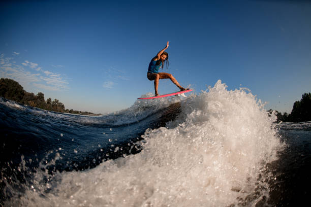 istock beautiful woman jumping on big splashing wave on surf style wakeboard. 1278043454