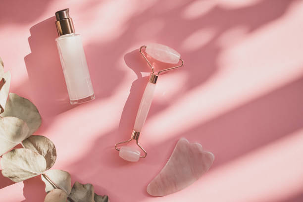 istock Massage with a quartz roller for the face with pink natural jade. Gouache massage tool, with beauty serum oil. Anti-aging and lifting at home. Facial care massage and relaxation concept. 1278043844