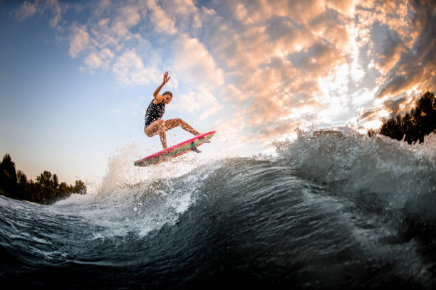 istock athletic woman skillfully jumping over big splashing wave on surf style wakeboard. 1278044107