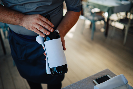 Waiter showing different types of wine to the guests in the restaurant.