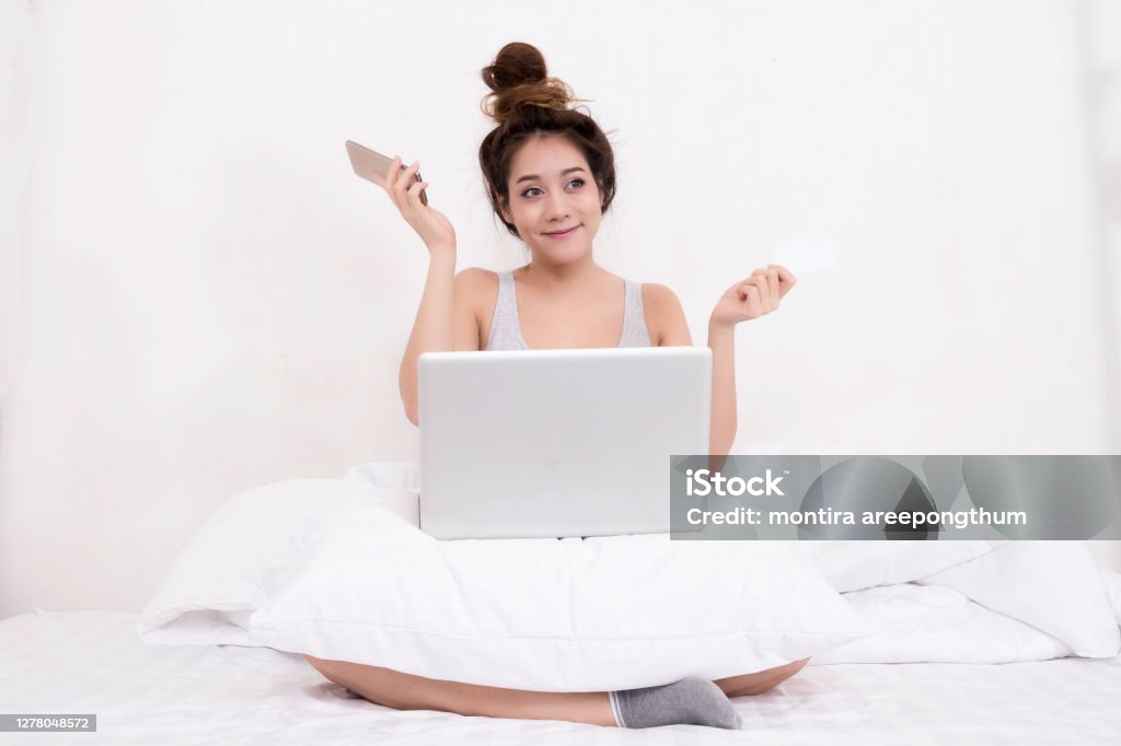 asian women in sporty pajamas sit or chat online with friends or shopping online and relax in