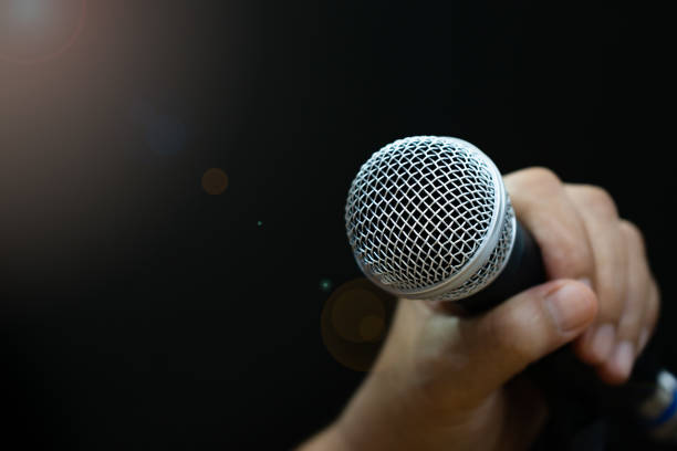 istock Hands holding Retro Microphones with lens light flare on front stage in pub bar or restaurant. Classic sing a song in evening and night show on black light background. 1278048691