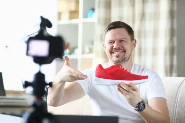 Photo of Man shows red sneaker in front camera, video blog