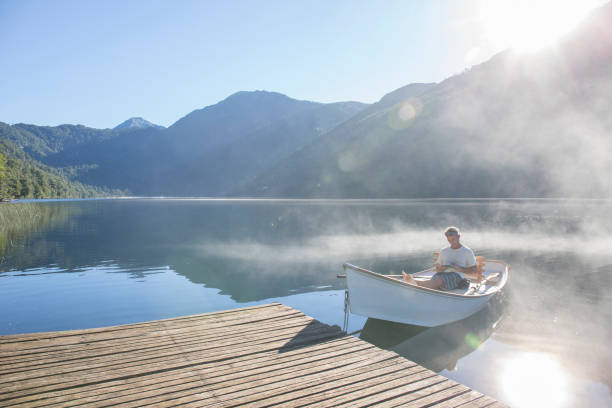 istock Man relaxes in rowboat, on tranquil lake 1278051997