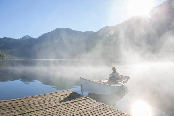 istock Man relaxes in rowboat, on tranquil lake 1278052001