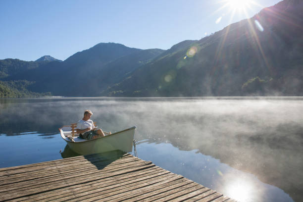 Man relaxes in rowboat, on tranquil lake