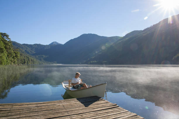 istock Man relaxes in rowboat, on tranquil lake 1278052188