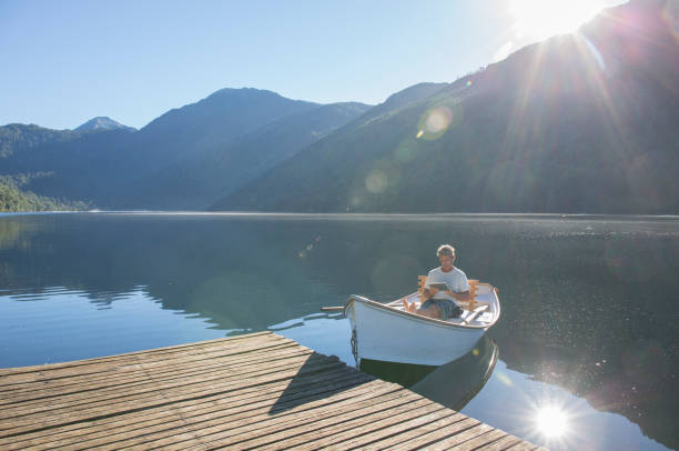 istock Man relaxes in rowboat, on tranquil lake 1278052235