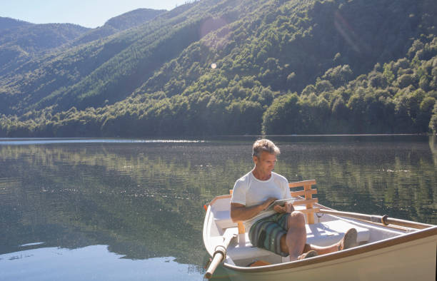 istock Man relaxes in rowboat, on tranquil lake 1278052278