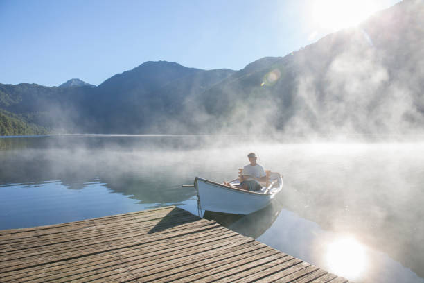 istock Man relaxes in rowboat, on tranquil lake 1278052364