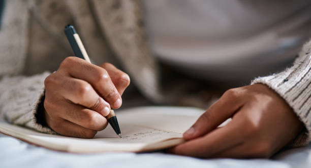 Day one of getting my life into gear Cropped shot of a man writing in a notebook on his bed at home Creative Writing stock pictures, royalty-free photos & images