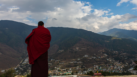 Thimphu, Mongolia - March 02, 2020: A Monk in the mountain around Thimphu near the Buddha Dordenma statue, during a prayer ceremony. Thimphu blurry in the background