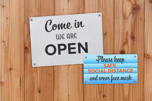 Come In We Are Open Sign On The Front Door Of Business Store With Please Keep Safe Social Distance And Wear Face Mask