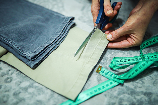 Hands That Measure and Cut Trouser Fabric With Tailor, Craft, Scissors and Tape Measure