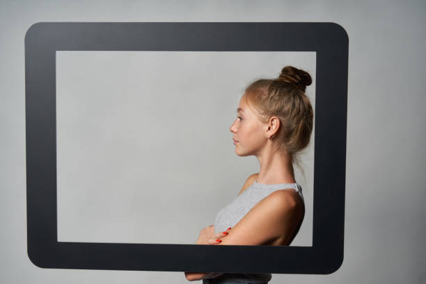 istock Profile of girl standing behind digital tablet frame and looking forward at blank copy space 1278061524
