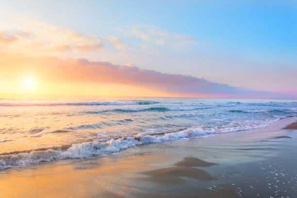 istock Evening sky setting sun in the sky over the ocean and waves on the sandy shore. 1278068432