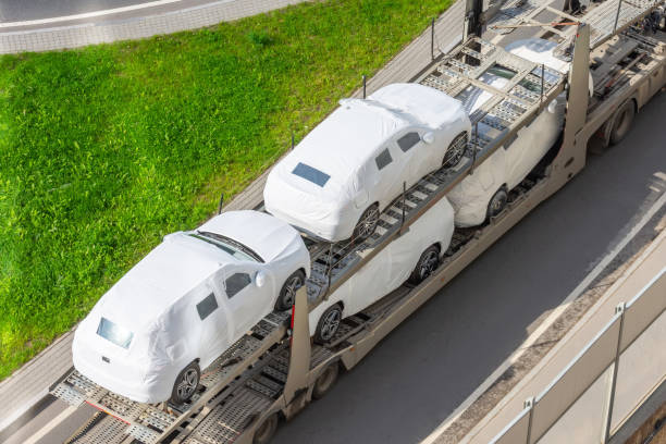 transport nowych samochodów pokrytych plandeką z tkaniny ochronnej na przyczepie ciężarówki. - truck semi truck car transporter vehicle trailer zdjęcia i obrazy z banku zdjęć