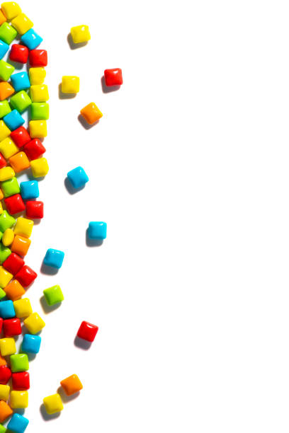 istock Candy. Multi-colored candies are located on the left on a white isolated background top view frame copy space. Chewing gum, and dragees are scattered. Vertical photo 1278070723