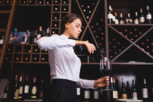 Brunette sommelier pouring wine from bottle in restaurant Brunette sommelier pouring wine from bottle in restaurant sommelier photos stock pictures, royalty-free photos & images