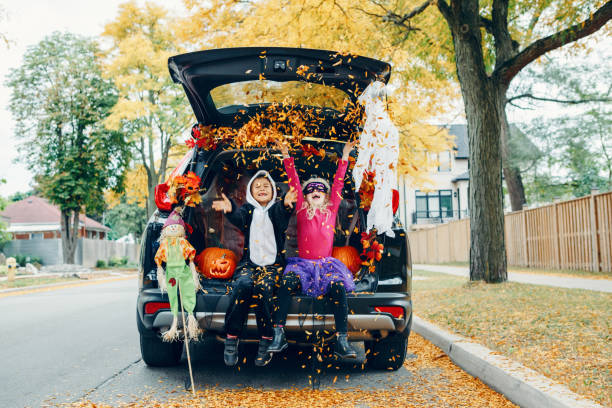 Trick or trunk. Children celebrating Halloween in trunk of car. Boy and girl with red pumpkins celebrating traditional October holiday outdoors. Social distance during coronavirus covid-19. Trick or trunk. Children celebrating Halloween in trunk of car. Boy and girl with red pumpkins celebrating traditional October holiday outdoor. Social distance during coronavirus covid-19. trunk furniture photos stock pictures, royalty-free photos & images