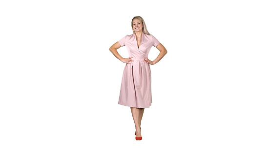 Full length portrait. Woman in dress with hands on hips walking while looking at camera on white background. Professional shot in 4K resolution. 005. You can use it e.g. in your commercial video, business, presentation, broadcast