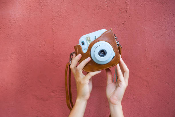 istock Woman hands holding a blue instax camera with a red wall on the background. 1278084804