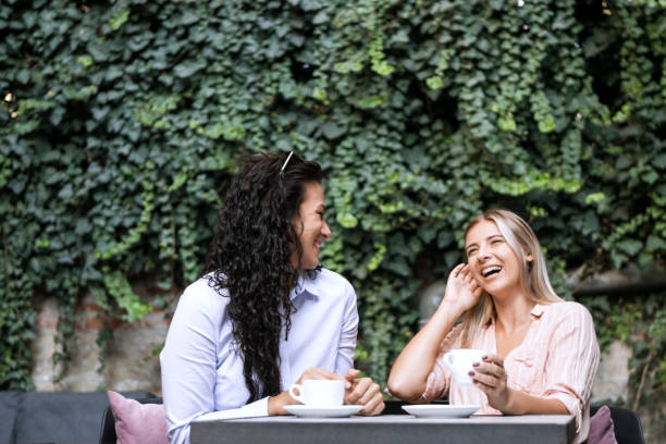 Women friends talking together drinking coffee