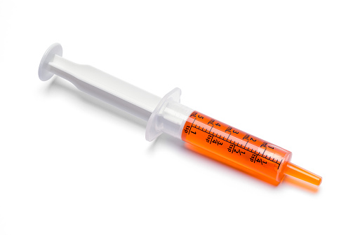 Oral Syringe With Orange Cough Medicine Dose.