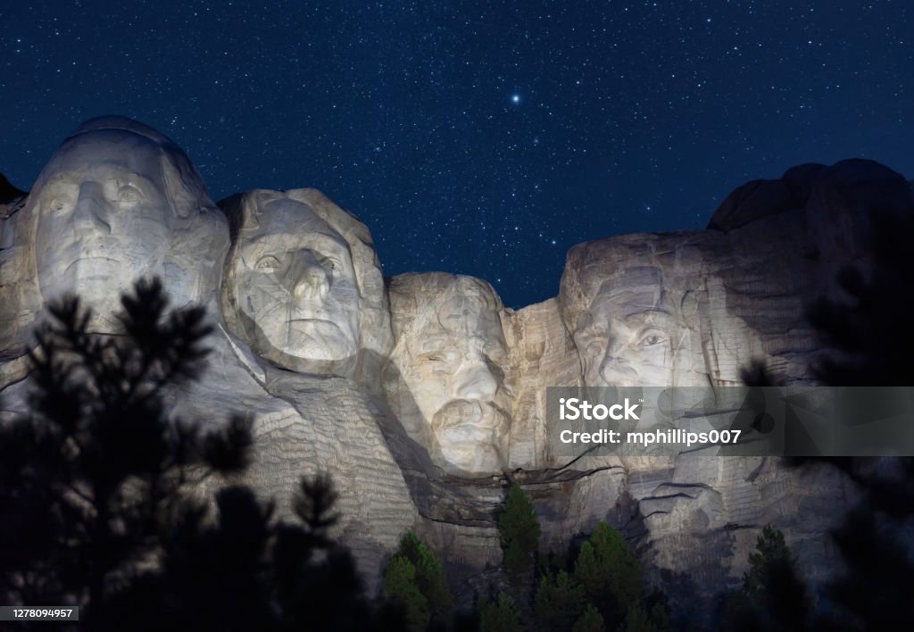 Mount Rushmore in South Dakota at Night with Starry Sky A view of Mount Rushmore in South Dakota at night with stars in sky and presidents illuminated. Mt Rushmore National Monument Stock Photo