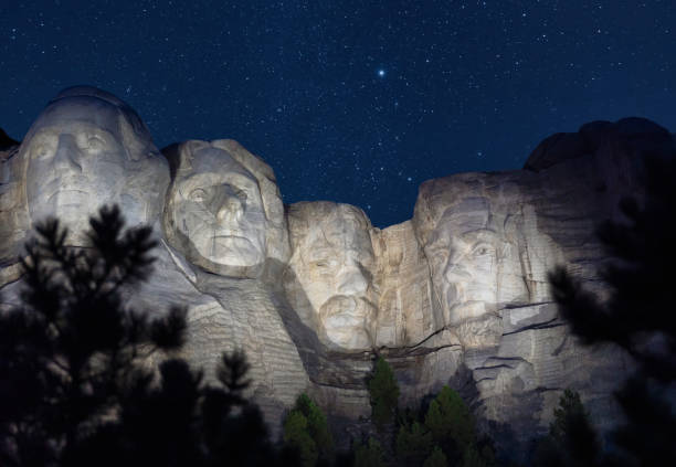 Mount Rushmore in South Dakota at Night with Starry Sky A view of Mount Rushmore in South Dakota at night with stars in sky and presidents illuminated. black hills national forest stock pictures, royalty-free photos & images