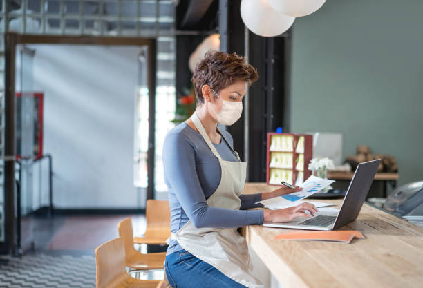 istock Business owner wearing a facemask while bookkeeping at a restaurant 1278100849