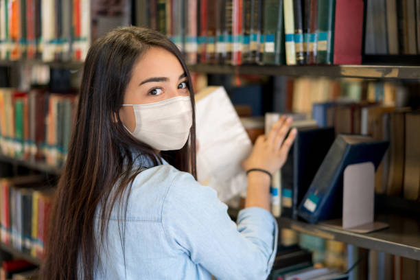 istock Student wearing a facemask at the library while looking at the camera 1278100884