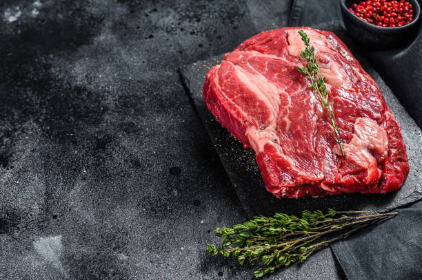 istock Fresh Raw meat Prime Black Angus Chuck roll steak.  Black background. Top view. Copy space 1278112108