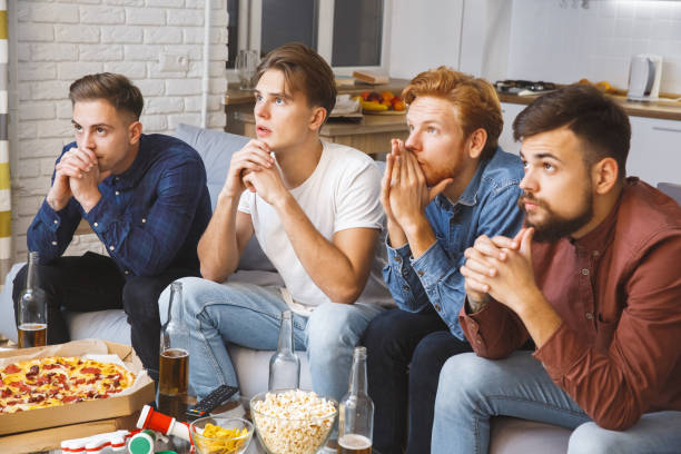 homens assistindo esporte na tv juntos em casa nervoso - american football football food snack - fotografias e filmes do acervo