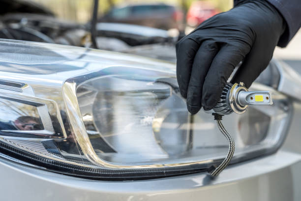 istock Male's hand holding new halogen car light bulb, mechanic servicing light 1278113330