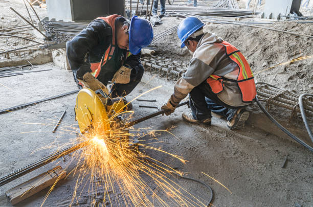 Man grinding metal tubes with protective equipment Heat sparks fly out in construction site due to cutting with a grinding machine power tool photos stock pictures, royalty-free photos & images