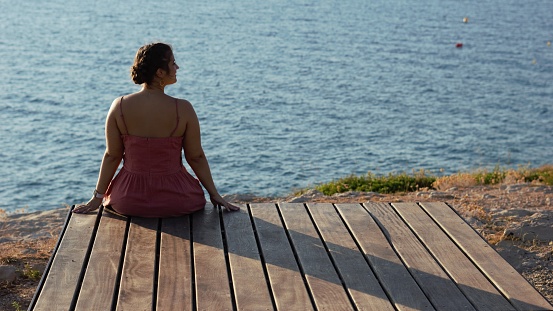 elegant young woman sitting looking at the sea