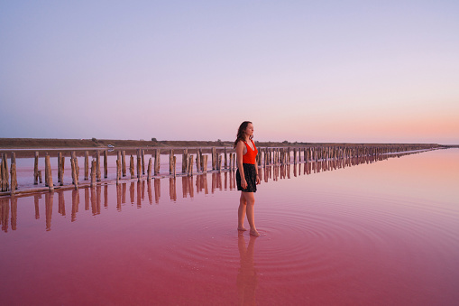 Young Caucasian  woman doing yoga  on the  pink salt lake in Ukraine