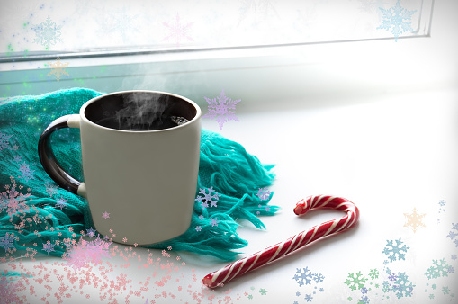 A mug of hot coffee is on the windowsill. Nearby lies an angry blue scarf and lollipop candy