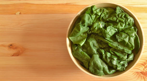 Fresh large spinach leafs in a wooden bowl stock photo