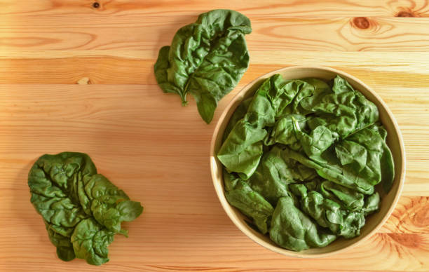 Fresh large spinach leafs in a wooden bowl stock photo