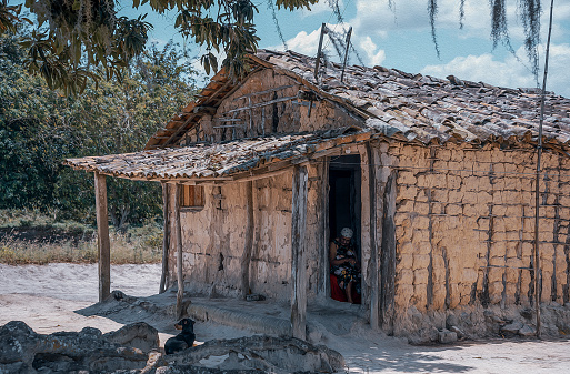 Moreno district, Pernambuco state, Brazil - October 12, 2019:Senior lady seated near the door of her humble house