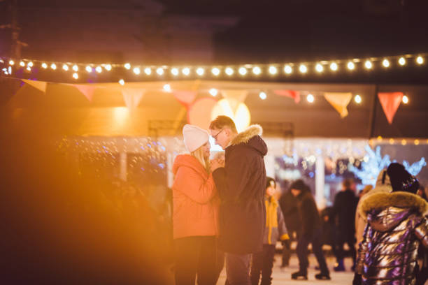 Beautiful couple have fun in ice arena. active date ice skating on ice arena in evening city square in winter Christmas Eve. St. Valentine's Day at the city ice rink. New Year's holidays in city Kiev. hermosa pareja se divierten en la arena de hielo. patinaje sobre hielo de cita activa en la arena de hielo en la plaza de la ciudad por la noche en la víspera de navidad de invierno. san valentín en la pista de hielo de la ciudad. vacaciones de año nuev